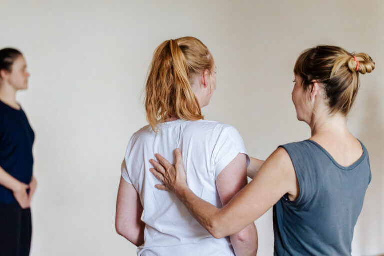 Pilates-Trainerin Doris Sattelberger gibt einer Teilnehmerin in einer Gruppe eine Haltungsanleitung